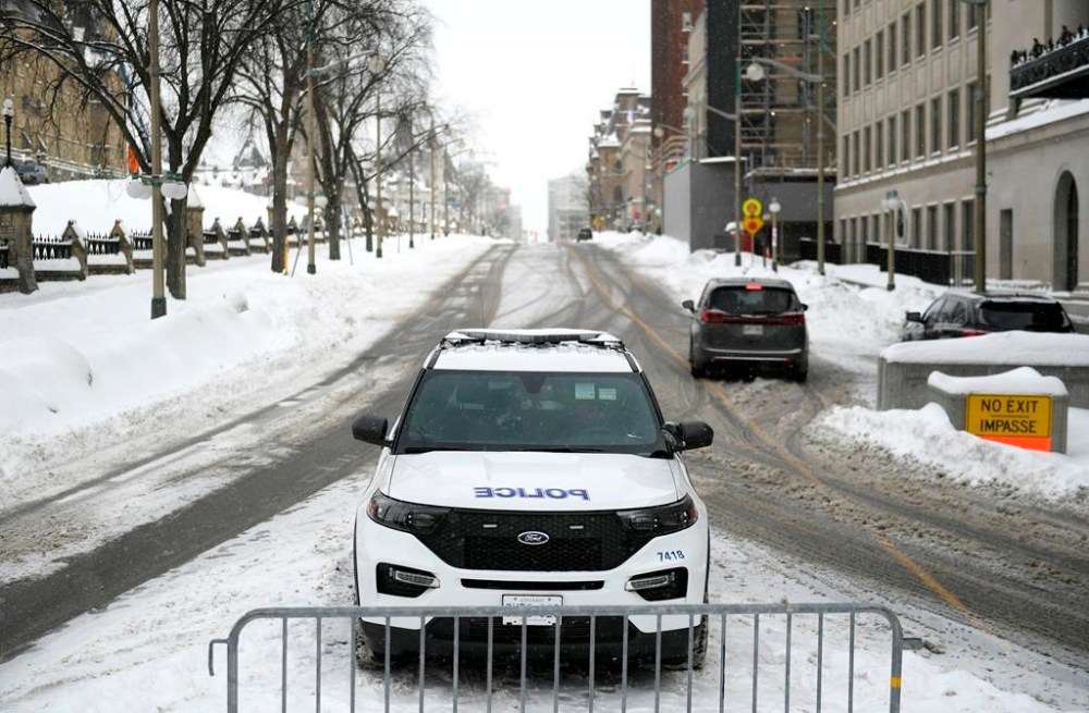An Ottawa Police officer sits in their cruiser on Wellington Street below Parliament Hill in Ottawa on Friday, Jan. 27, 2023. The criminal trial of two