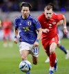 Takuma Asano, left, of Japan, is chased by Alistair Johnston of Canada during a friendly soccer match in Niigata, northern Japan, Friday, Oct. 13, 2023. (Kyodo News via AP)
