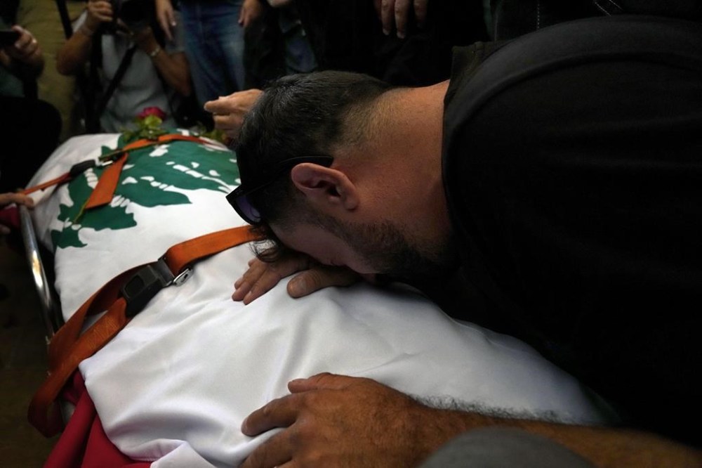 A friend of Reuters videographer Issam Abdallah who was killed by Israeli shelling mourns over his body during his funeral procession in his hometown of Khiam, southern Lebanon, Saturday, Oct. 14, 2023. Abdallah was killed Friday, Oct. 13, when an Israeli shell landed in a gathering of international journalists covering clashes on the border in south Lebanon. Six other journalists were injured in the incident. (AP Photo/Bilal Hussein)