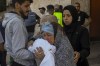 Outside al-Aqsa hospital in Deir el-Balah, central Gaza Strip, a Palestinian woman kisses the sheet-covered body of a child killed during an Israeli airstrike, Sunday, Oct. 15, 2023. (AP Photo/Adel Hana)
