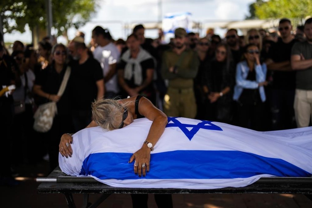 Antonio Macías' mother cries over her son's body covered with the Israeli flag at Pardes Haim cemetery in Kfar Saba, near Tel Aviv, Israel, Sunday, Oct. 15, 2023. Macias was killed when Hamas unleashed its attack on thousands of Jews attending a music festival in southern Israel earlier this month. (AP Photo/Francisco Seco)