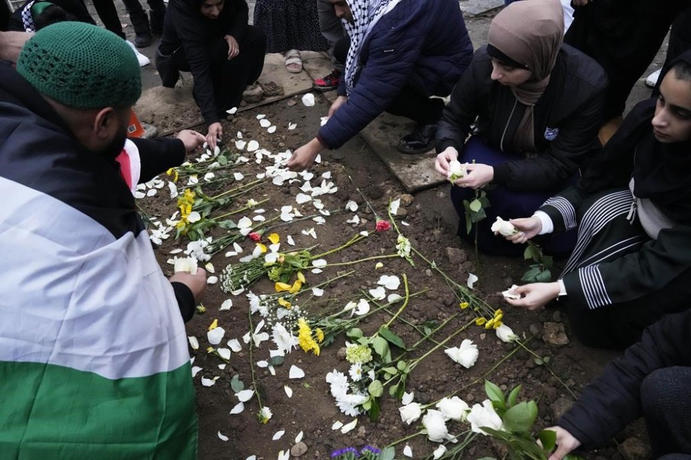 Supporters kneel at the grave of Wadea Al Fayoume in LaGrange, Ill., Monday, Oct. 16, 2023. An Illinois landlord accused of fatally stabbing the 6-year-old Muslim boy and seriously wounding his mother was charged with a hate crime after police and relatives said he singled out the victims because of their faith and as a response to the war between Israel and Hamas. (AP Photo/Nam Y. Huh)
