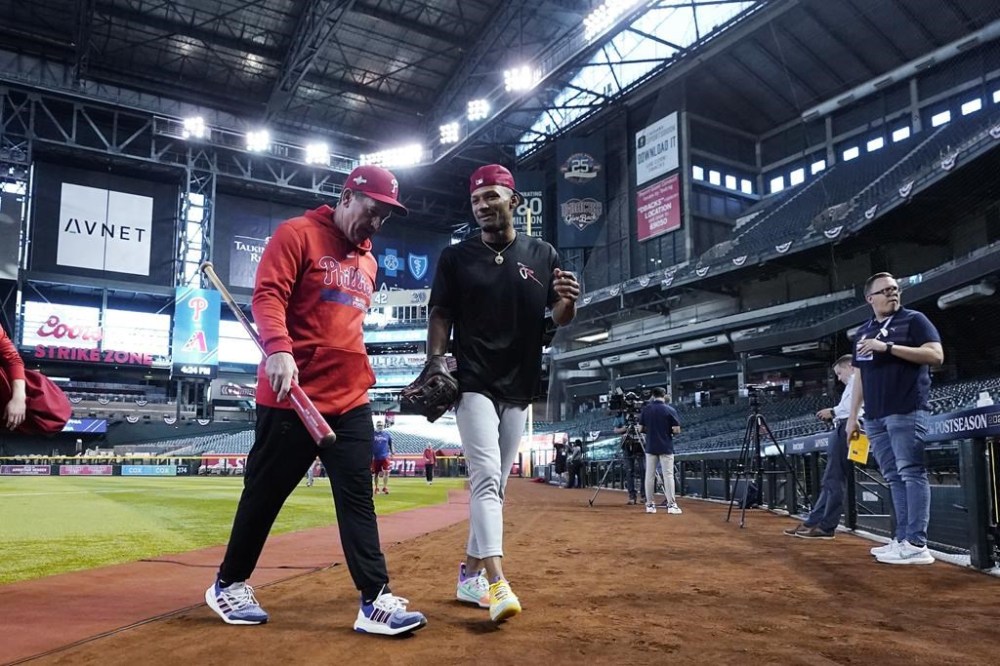 Philadelphia Phillies manager Rob Thomson, left, talks with Phillies Johan Rojas after a short workout session Wednesday, Oct. 18, 2023, in Phoenix. The Phillies will play Game 3 against the Arizona Diamondbacks in the baseball NL Championship Series on Thursday. (AP Photo/Ross D. Franklin)
