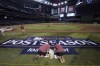 Members of the Chase Field grounds crew put the finishing touches on a MLB sign on the field Wednesday, Oct. 18, 2023, in Phoenix as the Arizona Diamondbacks and Philadelphia Phillies prepare to play Game 3 in the baseball NL Championship Series on Thursday. (AP Photo/Ross D. Franklin)