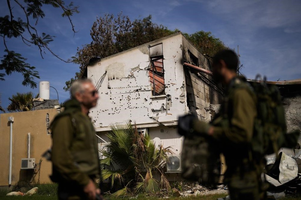 Soldiers walk next to a house damaged by Hamas militants at Kibbutz Kissufim in southern Israel, Saturday, Oct. 21, 2023. The Kibbutz was stormed by Hamas militants from the nearby Gaza Strip on Oct. 7, when they killed and captured many Israelis. (AP Photo/Francisco Seco)