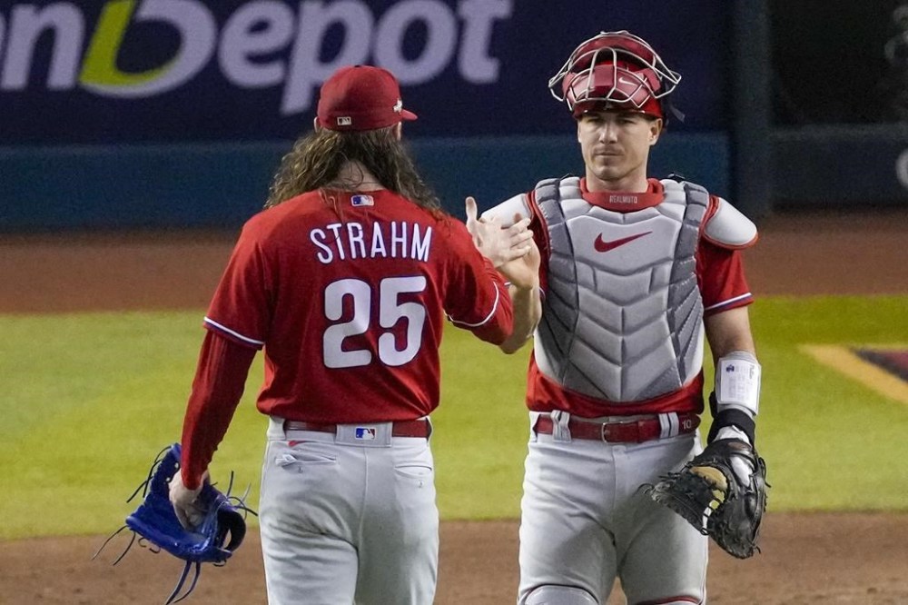 Philadelphia Phillies relief pitcher Matt Strahm and catcher J.T. Realmuto celebrate their win against the Arizona Diamondbacks in Game 5 of the baseball NL Championship Series in Phoenix, Saturday, Oct. 21, 2023. (AP Photo/Rick Scuteri)
