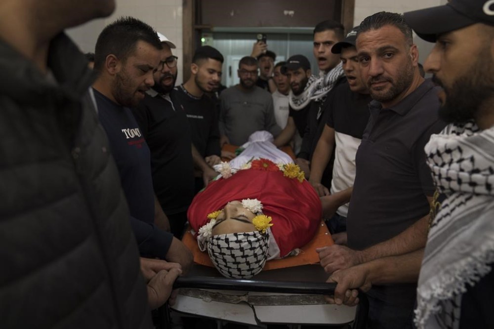 Mourners take the last look at the body of Sohaib al-Soos, 15, during his funeral in the West Bank city of Ramallah, Saturday, Oct. 21, 2023. Al-Soos was killed during an Israeli army raid in the town of Betunia last Friday, the Palestinian ministry of health said. (AP Photo/Nasser Nasser)