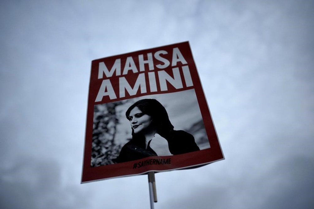 FILE - A woman holds a placard with a picture of Iranian woman Mahsa Amini during a protest against her death, in Berlin, Germany, on Sept. 28, 2022. A court in Iran sentenced two female journalists to up to seven years in prison for “collaborating” with the United States government among other charges, local reports said Sunday, Oct. 22, 2023. Both have been imprisoned for over a year following their coverage of the death of Mahsa Amini while in police custody in September 2022. (AP Photo/Markus Schreiber, File)
