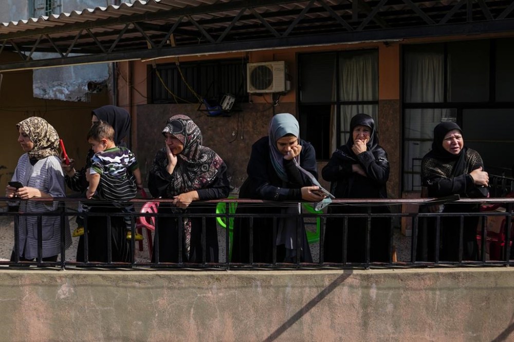 Women mourn as they watch from their balcony the funeral procession of Hezbollah fighter, Bilal Nemr Rmeiti, who was killed by Israeli shelling, during his funeral procession in Majadel village, south Lebanon, Sunday, Oct. 22, 2023. (AP Photo/Hassan Ammar)