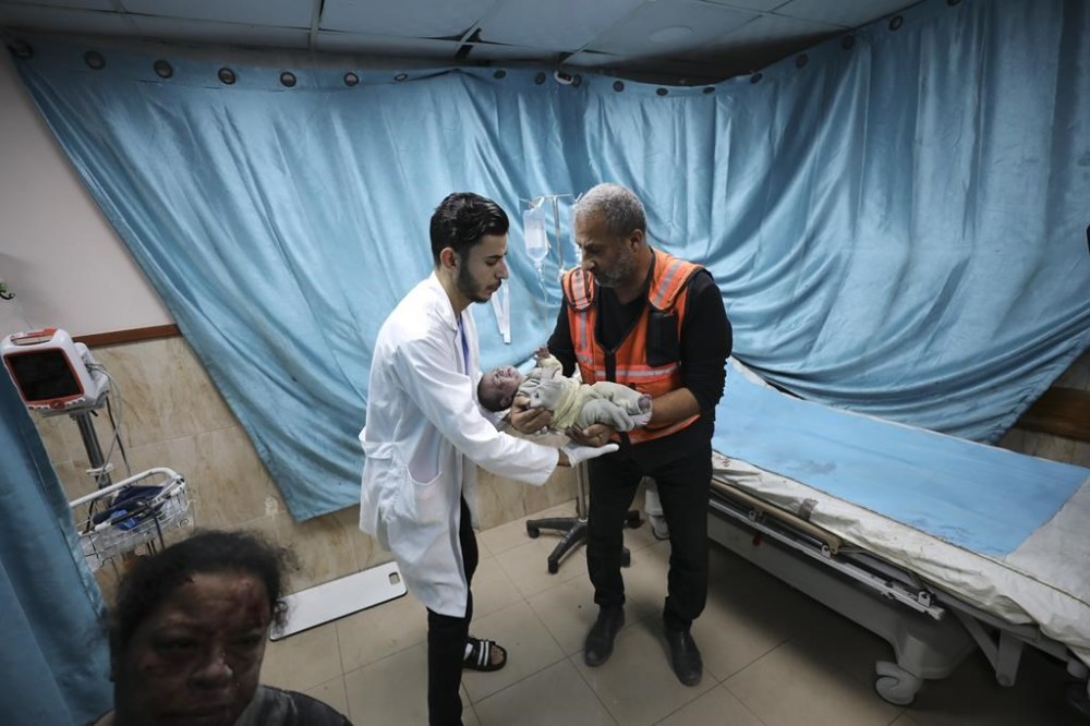 A Palestinian medic holds a child wounded in Israeli air strike on the Gaza Strip, in Deir el-Balah, Sunday, Oct. 22, 2023. (AP Photo/Ali Mahmoud)