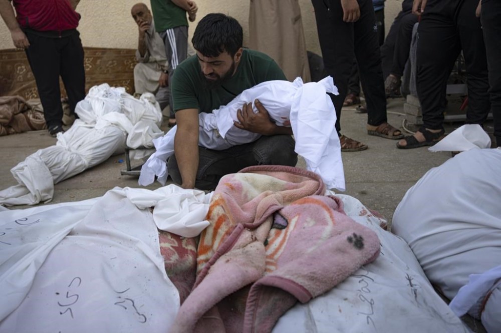 A Palestinian man holds the body of his child next to others killed in the Israeli bombardment of the Gaza Strip at Al-Aqsa Hospital in Deir Al-Balah, Sunday, Oct. 22, 2023. ( AP Photo/Fatima Shbair)