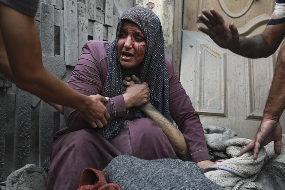 A wounded Palestinian woman cries as she holds the hand of her dead relative outside her home following Israeli airstrikes that targeted their neighbourhood in Gaza City, Monday, Oct. 23, 2023. (AP Photo/Abed Khaled)