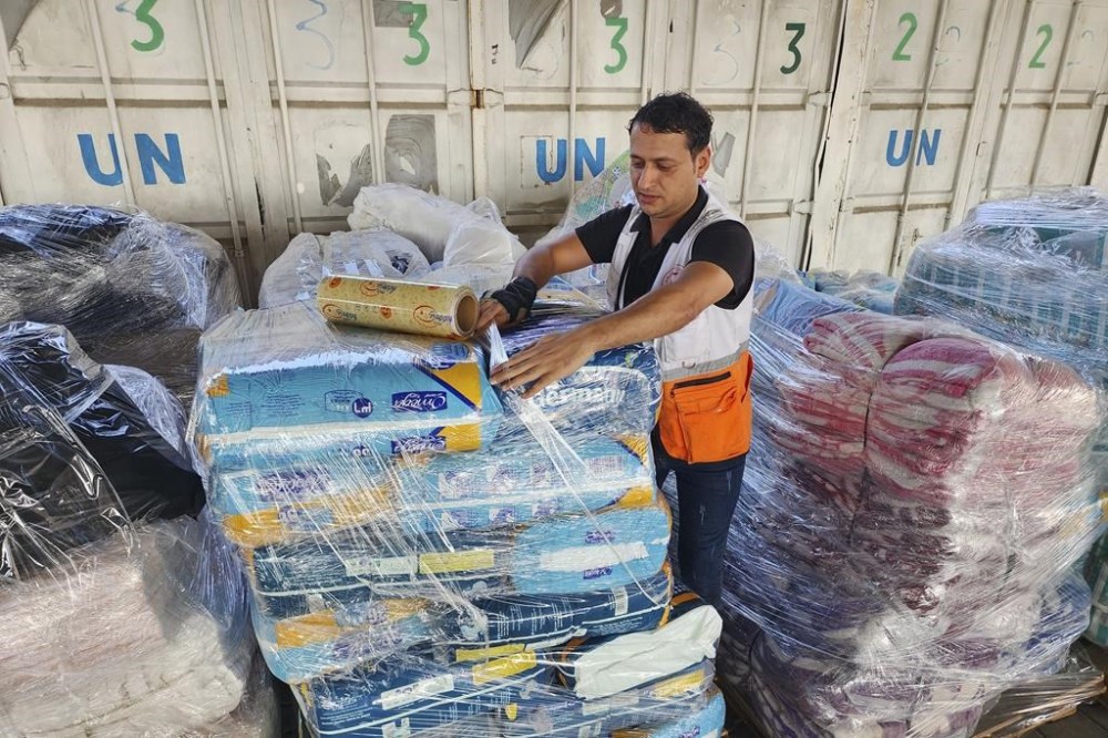United Nations and Red Crescent workers prepare the aid for distribution to Palestinians at UNRWA warehouse in Deir Al-Balah, Gaza Strip, on Monday, Oct. 23, 2023. (AP Photo/Hassan Eslaiah)