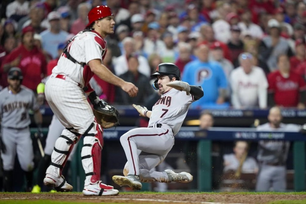 Arizona Diamondbacks' Corbin Carroll scores past Philadelphia Phillies catcher J.T. Realmuto on a single by Gabriel Moreno during the fifth inning in Game 7 of the baseball NL Championship Series in Philadelphia Tuesday, Oct. 24, 2023. (AP Photo/Matt Slocum)