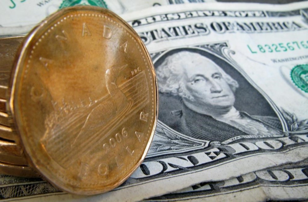 A loonie sits on American dollar bills on Sept. 20, 2007 in Montreal. The Canadian dollar has dipped against the US dollar following the Bank of Canada's decision to hold its key interest rate at five per cent. THE CANADIAN PRESS/Paul Chiasson