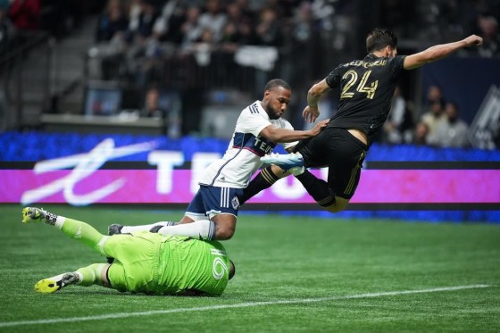 Los Angeles FC goalkeeper Maxime Crepeau, bottom left, makes the save as Vancouver Whitecaps' Junior Hoilett, centre, and Los Angeles' Ryan Hollingshead (24) tumble over him during the second half of an MLS soccer match, in Vancouver Saturday. (Darryl Dyck / The Canadian Press)