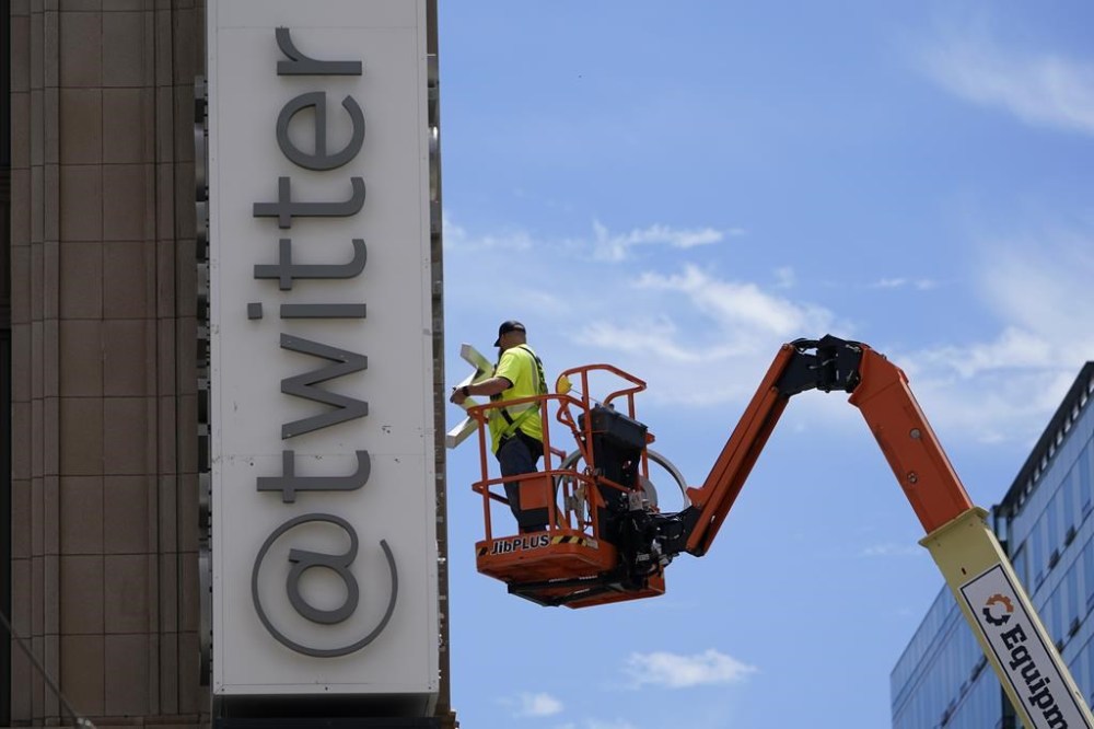 FILE - A workman removes a character from a sign on the Twitter headquarters building in San Francisco, July 24, 2023. One year ago, Elon Musk began transforming the social media platform into what is now known as X. (AP Photo/Godofredo A. Vásquez, File)
