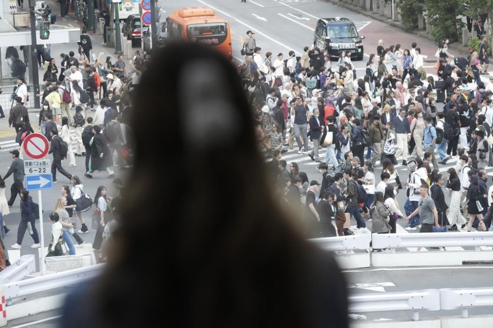 Visitors walk at the Shibuya pedestrian crossing Friday, Oct. 27, 2023, in Tokyo. Ahead of this year's Halloween weekend, Tokyo's busy shopping, business and entertainment district of Shibuya is trying hard to shoo away visitors. Banners across town say no drinking and no Halloween events on the street, and town officials are cordoning off the landmark statue of Hachi with protective walls.(AP Photo/Eugene Hoshiko)