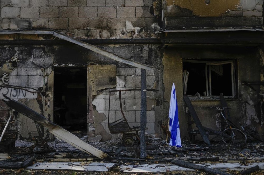 The son of a Canadian woman believed to be among Hamas hostages in Gaza wants the world to push for an end to to the fighting, and he fears Israel’s escalating offensive could end all chance of her surviving. An Israeli flag is placed next to a house destroyed by Hamas militants in Kibbutz Be'eri, Israel, Sunday, Oct. 22, 2023. THE CANADIAN PRESS/AP-Ariel Schalit
