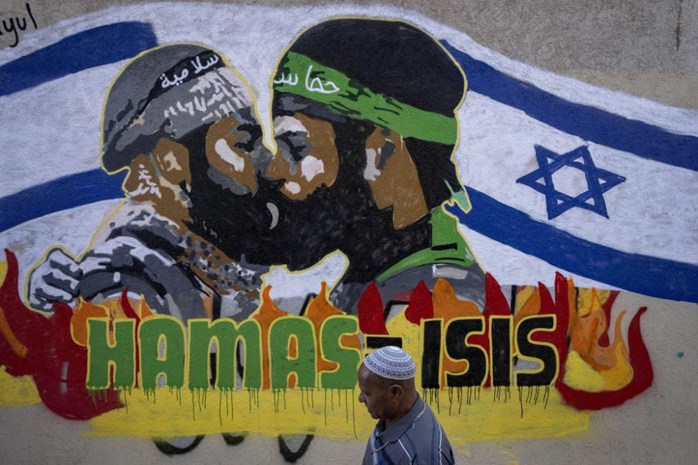 A man walks past a newly painted graffiti that reads Hamas equal ISIS, in Tel Aviv, Israel, Monday, Oct. 30, 2023. On Oct. 7, more than 1,400 people, mostly Israeli civilians, were killed and some 230 captured in an unprecedented, cross-border attack by Hamas militants from the Gaza Strip. (AP Photo/Oded Balilty)