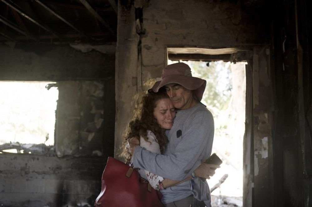 Residents of Kibbutz Nir Oz in southern Israel weep together in the ruins of the home of Carmela Dan, 80, Monday, Oct. 30, 2023. She was killed when the kibbutz was overran by Hamas militants on Oct. 7, killing or capturing a quarter of its community. (AP Photo/Maya Alleruzzo)