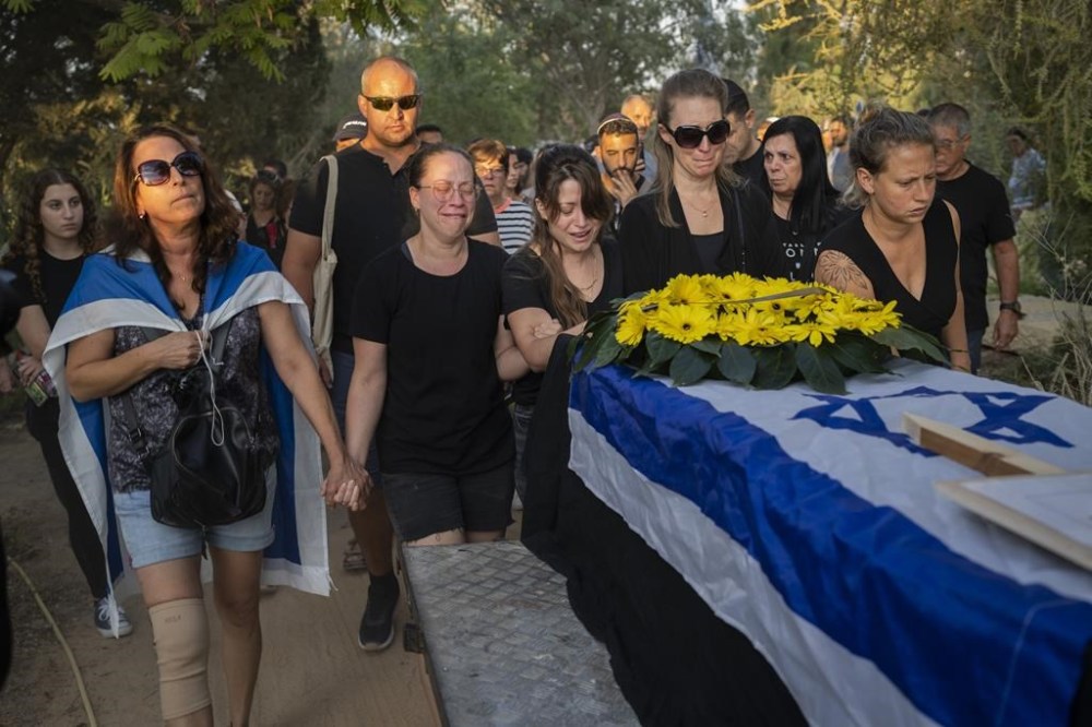 Relatives attend the funeral of Albert Miles, 81, at the Kibbutz Revivim cemetery, south Israel, Monday, Oct. 30, 2023. Albert Miles was killed during the Hamas attack on Oct. 7, in Kibbutz Be'eri near the border with the Gaza Strip. (AP Photo/Bernat Armangue)