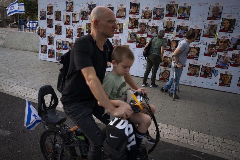 People look at photographs of hostages. mostly Israeli civilians who were abducted during the Oct. 7, unprecedented Hamas attack on Israel, in Tel Aviv, Israel Monday, Oct. 30, 2023. (AP Photo/Oded Balilty)