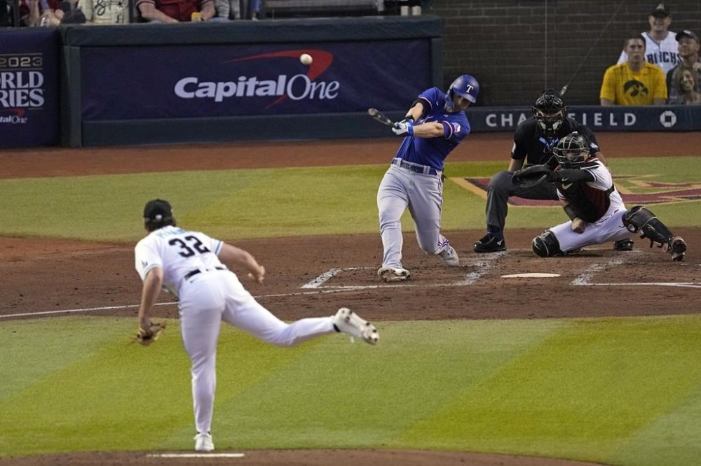 Texas Rangers' Corey Seager, center, hits a two-run home run off Arizona Diamondbacks starting pitcher Brandon Pfaadt (32) during the third inning in Game 3 of the baseball World Series Monday, Oct. 30, 2023, in Phoenix. (AP Photo/Ross D. Franklin)