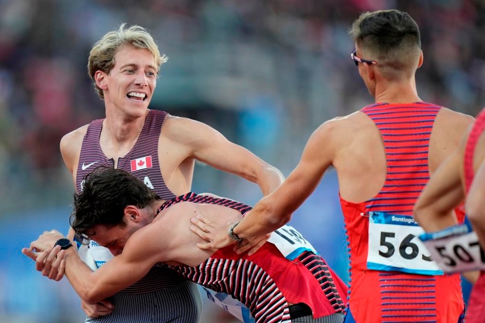 Canada's Robert Joseph Heppenstall, centre, embraces teammate Charles Philibert-Thiboutot during the men's 1500m final at the Pan American Games, in Santiago, Chile, Thursday, Nov. 2, 2023. THE CANADIAN PRESS/Frank Gunn
