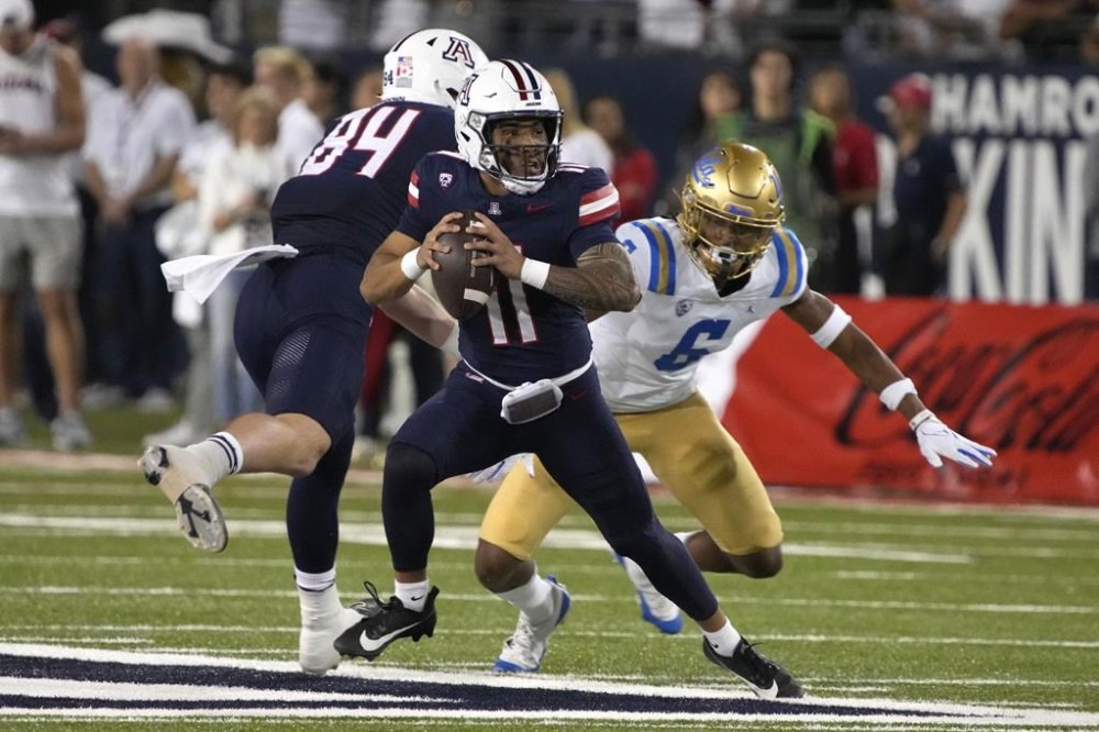 Arizona quarterback Noah Fifita (11) avoids UCLA defensive back John Humphrey during the first half of an NCAA college football game, Saturday, Nov. 4, 2023, in Tucson, Ariz. (AP Photo/Rick Scuteri)