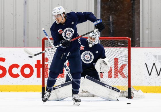 Mark Scheifele tips the puck in front of goaltender Connor Hellebuyck as the Jets practice in Winnipeg on Oct. 9. (John Woods / Winnipeg Free Press files)