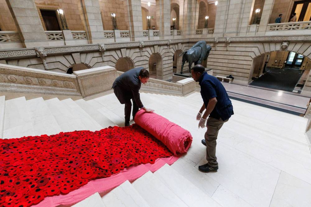 Manitoba Legislative building maintenance staff, Tesfay Fanta (right) and Brad Robertson (left), Manitoba’s Chief of Protocol, unroll a section of the Poppy Blanket. First unveiled in November of 2019, the Poppy Blanket is an 85 foot long collection of over 8,000 handmade poppies and thousands of dedicated ribbons. It was made in less than a year between 2018 and 2019 after she reached out to the Handmade Winnipeg Facebook group and they were soon joined by hundreds of other volunteers. (Mike Deal / Winnipeg Free Press)