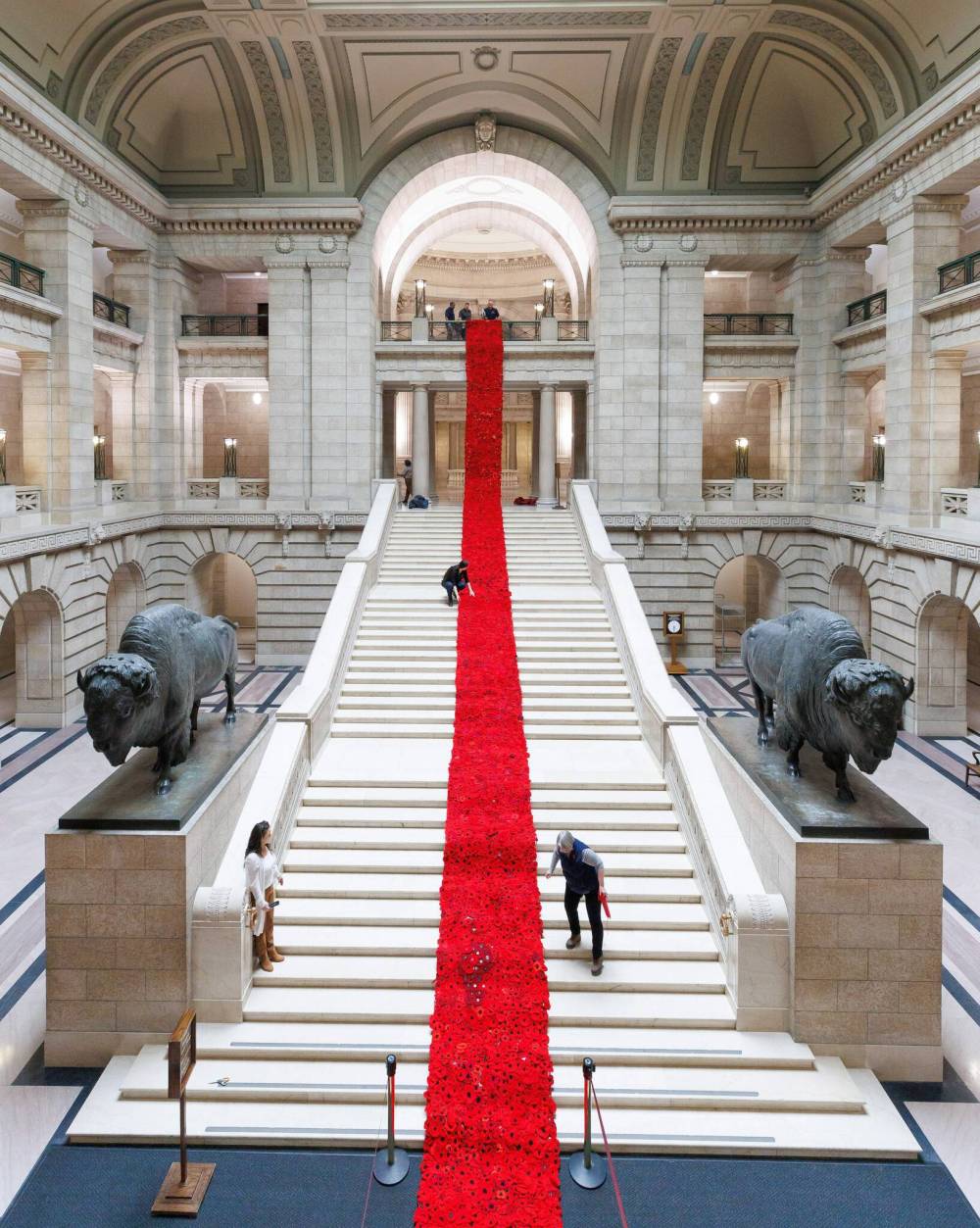 The Poppy Blanket is unrolled by creator, Sheila Lee Restall, and Manitoba Legislative building maintenance staff, including Brad Robertson, Chief of Protocol, Monday morning. (Mike Deal / Winnipeg Free Press)
