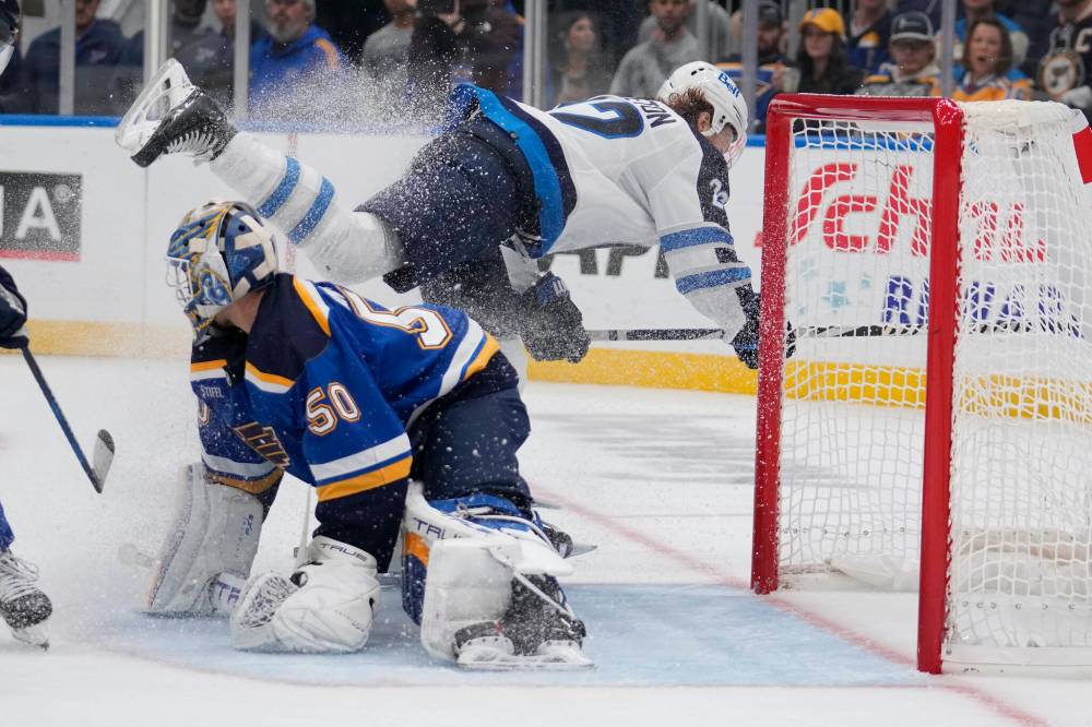 Jeff Roberson / The Associated Press
Jets forward Mason Appleton flies over Blues goalie Jordan Binnington after Binnington stopped him on a breakaway Tuesday night in St. Louis.