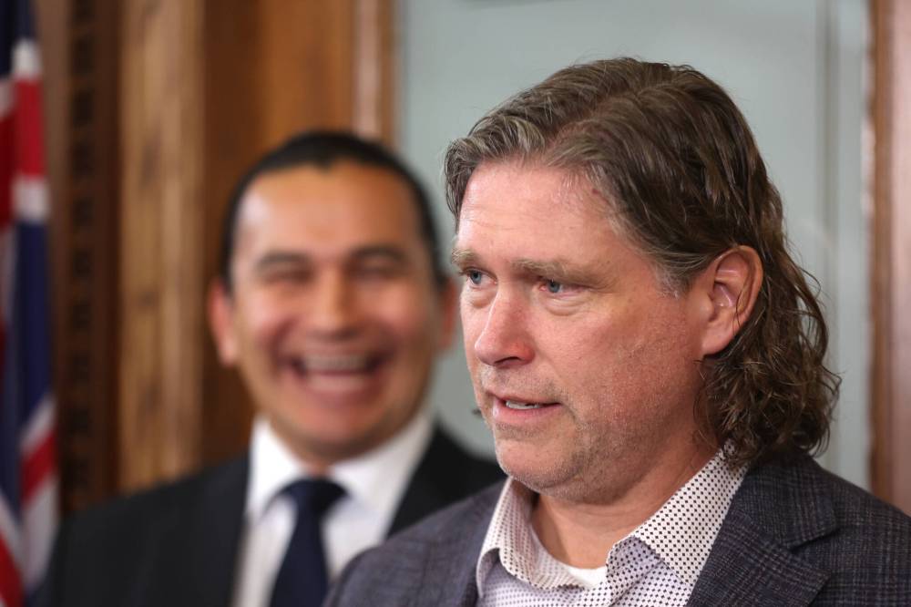 Manitoba Premier Wab Kinew laughs in the background while a straight-faced Brandon Mayor Jeff Fawcett cracks a joke. (Matt Goerzen/The Brandon Sun)