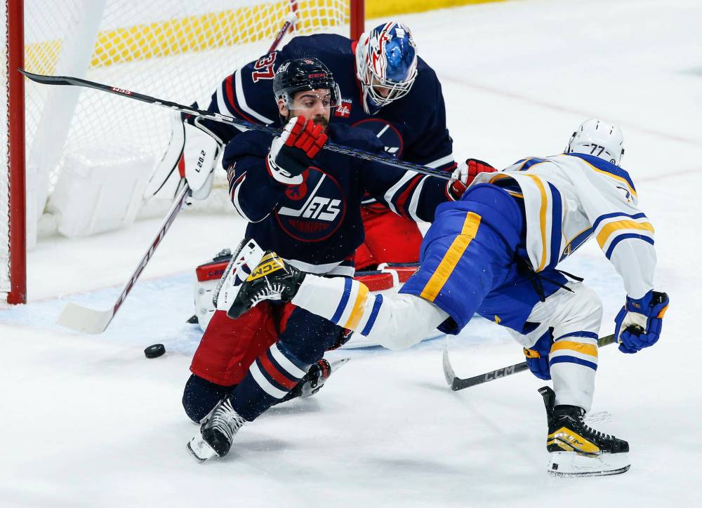 John Woods / THE CANADIAN PRESS
Jets netminder Connor Hellebuyck saves a shot from Buffalo’s JJ Peterka on Friday while D-man Dylan DeMelo defends the crease.