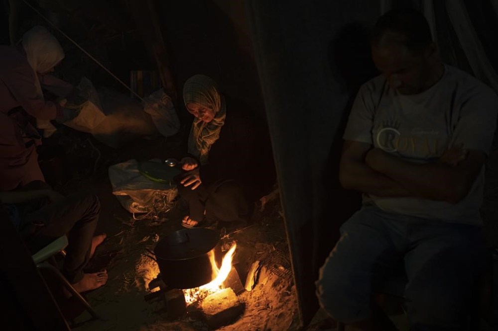 FILE - Palestinians displaced by the Israeli bombardment of the Gaza Strip sit by a fire in a UNDP-provided tent camp in Khan Younis, Wednesday, Nov. 1, 2023. With the Israel-Hamas war in its second month and more than 10,000 people killed in Gaza, trapped civilians are struggling to survive without electricity or running water. Each day has become a mind-numbing cycle of searching for bread and water and waiting in lines. A sense of desperation has strained Gaza's close-knit society. (AP Photo/Fatima Shbair, File)