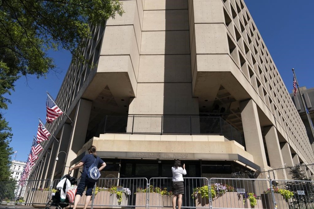 FILE - People take photos of the FBI building headquarters in Washington, Aug. 13, 2022. A federal judge in Washington is weighing whether to hold in contempt Catherine Herridge, a veteran journalist who has refused to identify her sources for stories about a Chinese scientist who was investigated by the FBI but never charged. (AP Photo/Jose Luis Magana, File)