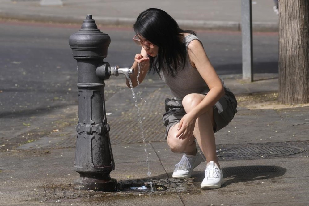 FILE - A woman drinks from a public fountain tap amid extreme heat in Madrid, Spain, Aug. 9, 2023. The world is off track in its efforts to curb global warming, a new international report calculates Tuesday, Nov. 14. (AP Photo/Paul White)