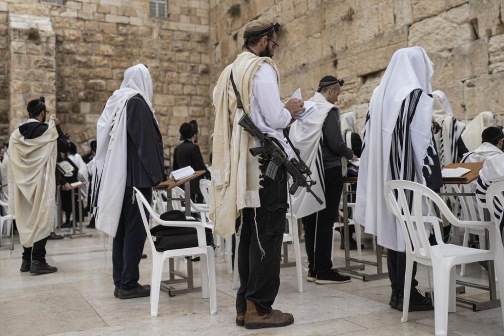 An off-duty member of Israel's security forces joins worshippers at the Western Wall, the holiest site where Jews can pray, in the Old City of Jerusalem, Tuesday, Nov. 14, 2023. Tens of thousands of Israeli reservists have been called up for action for the war against Hamas, while other security personnel have begun to carry weapons in public, following the Islamic militant group's deadly cross-border attack on Oct. 7. (AP Photo/Ohad Zwigenberg)