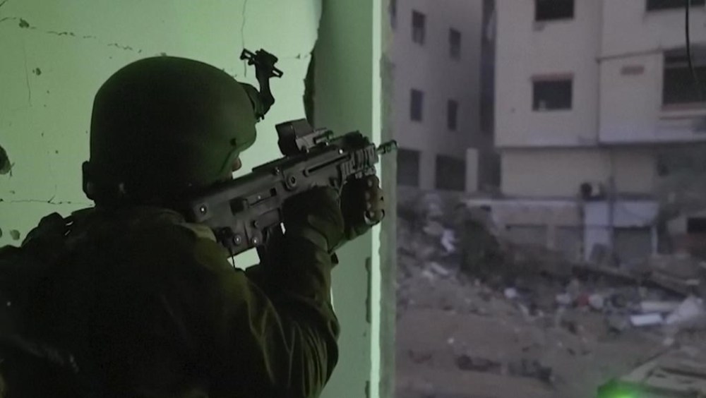 In this image taken from a video released by the Israeli Defense Forces on Tuesday, Nov. 14, 2023, an Israeli soldier holds a weapon in Gaza City. The Israeli military released footage on Tuesday that it said shows joint operational activity of two army brigades in its advancement on the ground in Gaza Strip. (Israel Defense Forces via AP)