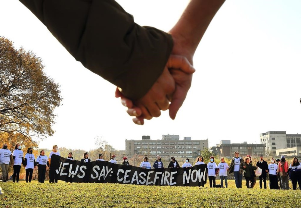 Demonstrators calling for a ceasefire in the Gaza Strip join hands on the field at Magazine Beach after blocking traffic on the nearby BU Bridge for several hours Thursday, Nov. 16, 2023 in Cambridge, Mass. (John Tlumacki/The Boston Globe via AP)