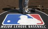 FILE - A baseball player stands on the Major League Baseball, MLB, logo on April 24, 2013, in Chicago. Police say the Detroit Tigers complex in the Dominican Republic was targeted Wednesday, Oct. 18, 2023, in the latest robbery of a Major League Baseball facility in the country. (AP Photo/Charles Rex Arbogast, File)