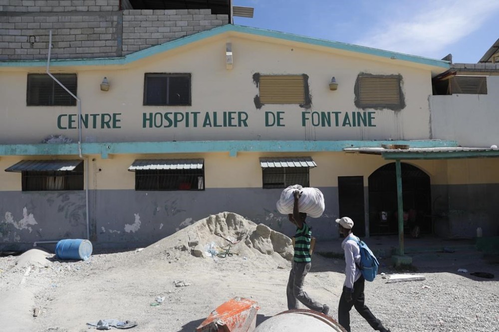 People walk past the temporarily closed Fontaine Hospital Center the day after it was attacked in the Cité Soleil area of Port-au-Prince, Haiti, Thursday, Nov. 16, 2023. A heavily armed gang surrounded the hospital on Wednesday, trapping women, children and newborns inside until police rescued them, according to the director of the medical center. (AP Photo/Odelyn Joseph)