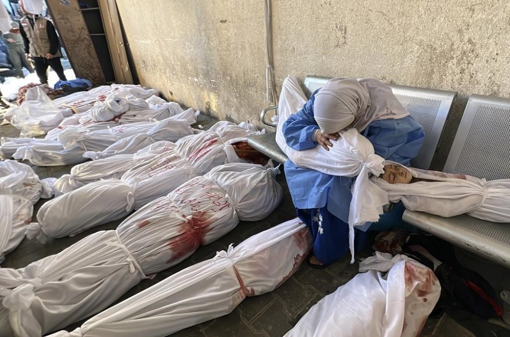 A Palestinian woman mourns over the body of a child as she sits by bodies of Palestinians killed by Israeli airstrikes on Jabaliya refugee camp, at the Indonesian hospital, northern Gaza Strip, Saturday, Nov. 18, 2023. (AP Photo/Ahmed Alarini)