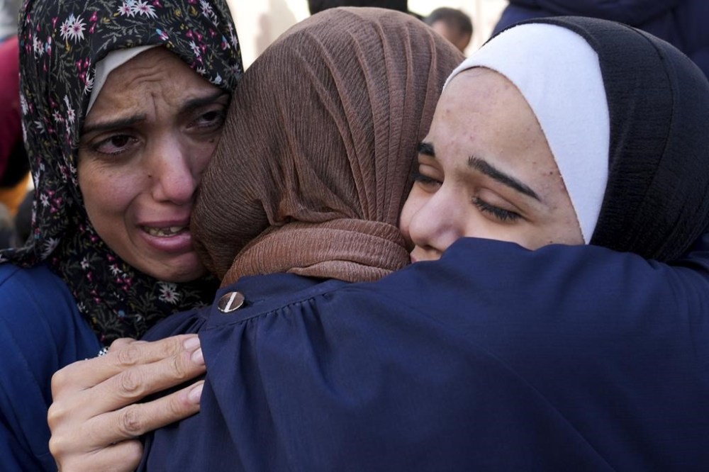 Palestinians mourn relatives killed in the Israeli bombardment of the Gaza Strip in front of the morgue in Deir al Balah, Sunday, Nov. 19, 2023. (AP Photo/Hatem Moussa)