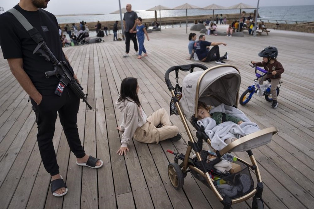 An off-duty Israeli soldier and his family enjoy the day at the Tel Aviv port on the second day of a cease-fire between Israel and Hamas, Saturday, Nov. 25, 2023. Israel prepared Saturday to release several dozen Palestinian prisoners in exchange for around 14 hostages held by Hamas in Gaza. (AP Photo/Oded Balilty)