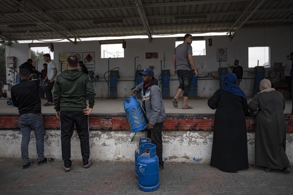 Palestinians line up for cooking gas during the second day of the temporary ceasefire between Hamas and Israel in Khan Younis, Gaza Strip, Saturday, Nov. 25, 2023. (AP Photo/Fatima Shbair)