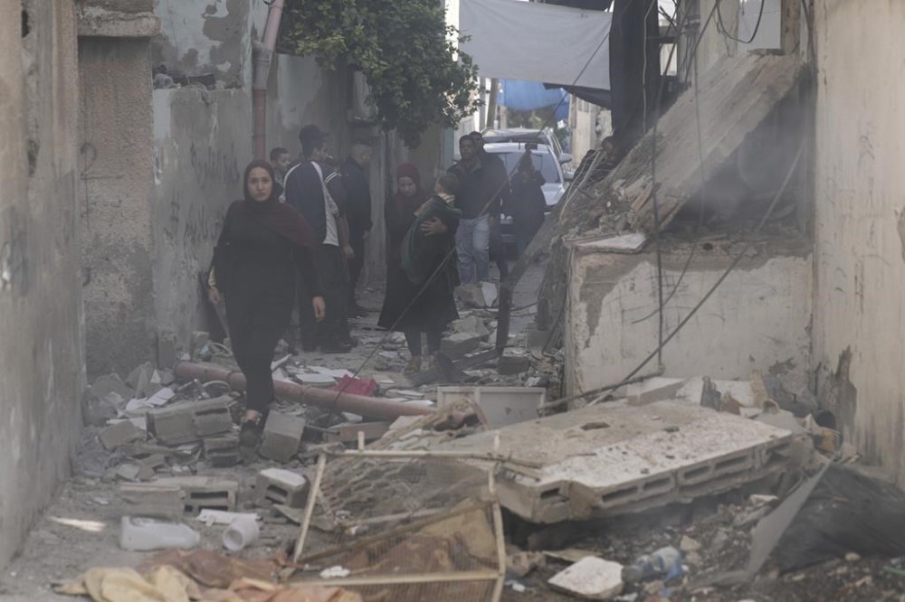 Palestinians walk by a damaged building following an Israeli army operation in Jenin refugee camp, West Bank, Sunday, Nov. 26, 2023. Israeli forces operating in the occupied West Bank killed at least eight Palestinians in a 24-hour period, Palestinian health officials said Sunday. (AP Photo/Majdi Mohammed)