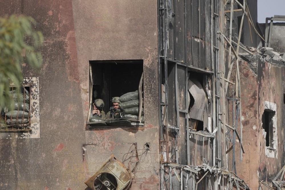 An Israeli soldier looks at Palestinians fleeing south at Salah al-Din road in central Gaza Strip on Sunday, Nov. 26, 2023, on the third day of a temporary ceasefire between Hamas and Israel. (AP Photo/Hatem Moussa)